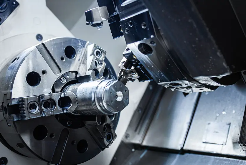 Five-axis CNC milling machine cutting a precision metal part.